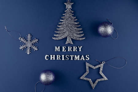 Festive greeting card. Merry christmas lettering on blue paper with sperkling blue toysの写真素材