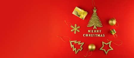 Festive greeting card. Merry christmas lettering on red paper with golden glittering toys. banner