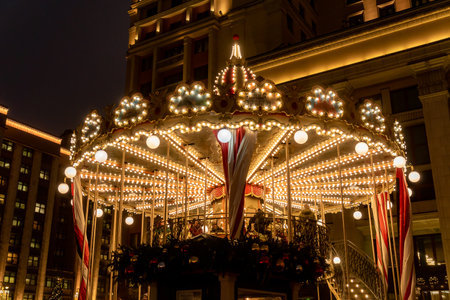 Moscow, Russia - December 18, 2019: People on colorful merry go round on christmass and new year holidays. Festive Manezhnaya Square in duskのeditorial素材