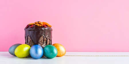 Easter cake and colored eggs on pink background. Holiday food and easter concept. Banner with copyspase.の写真素材
