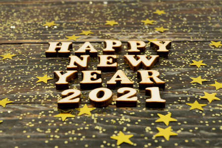 Happy New Year 2021. Symbol made from wooden letters and numbers 2021 on wooden background with golden confetti.の写真素材
