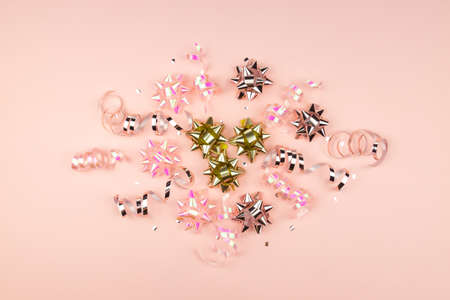 Christmas or New Year composition with pink sparkling ribbons and gift bows decorations on pink...