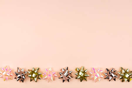 Christmas or New Year composition with golden goft bow and sparkling shiny decoration on pink background. Party Celebration creative conceptの写真素材