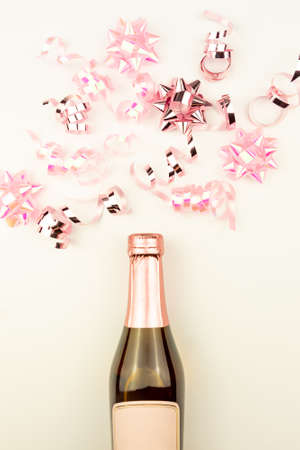 Christmas or New Year composition with pink sparkling ribbons, champagne and gift bows decorations on white backgroundの写真素材