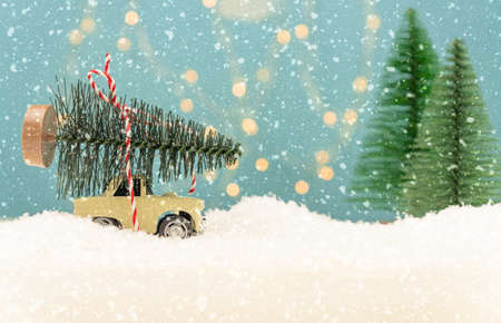 Christmas or New year card with toy car and christmas tree miniature and Christmas bokeh lights on background.の写真素材