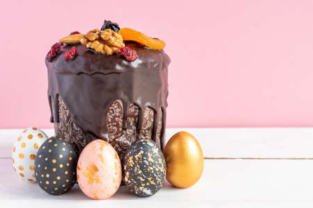 Easter cake and colored eggs on pink background. Holiday food and easter concept