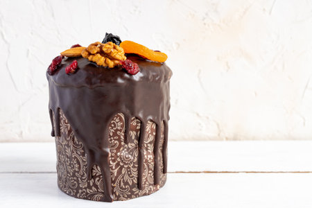 Easter cake or kulitch with glazed with chocolate and decorated with nuts, dried berries and fruits...