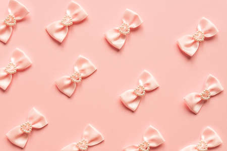 Pink satin bows with pearl hearts pattern on pink background. Festive concept for St Valentine's Day.の写真素材