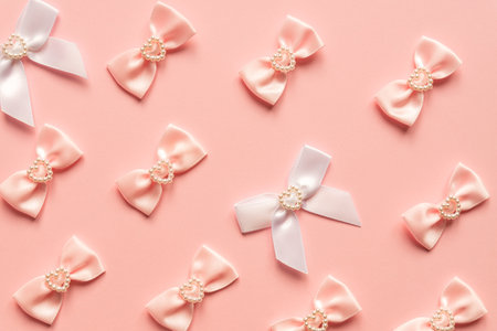 Pink satin bows with pearl hearts pattern on pink background. Festive concept for St Valentine's Day.の写真素材