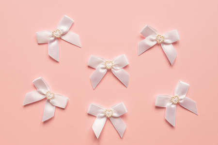 Pink satin bows with pearl hearts pattern on pink background. Festive concept for St Valentine's...