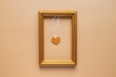 Valentine's day or Wedding romantic concept. golden photo frame with wooden heart inside on beige...