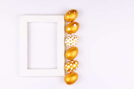 Easter festive decoration. Top view of easter eggs colored with golden paint and empty mock-up photo...