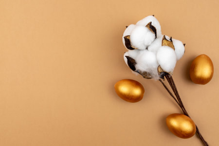Festive easter layout. Cotton flower branch and gold painted eggs on beige background. Neutral colorsの写真素材