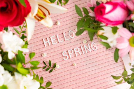 Text Hello Spring on pink letter board and frame of blooming flowers. Concept Springtime mood and happinessの写真素材