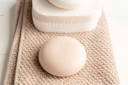 Close up of soap bar lies on towel background next to face sponges. Eco friendly space and personal hygiene concept.の写真素材