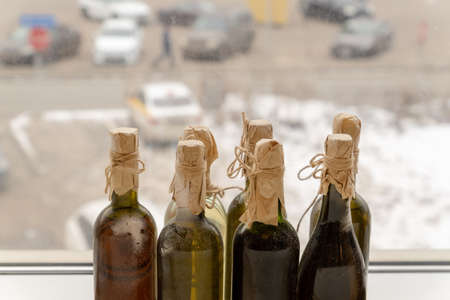 Dusty wine bottles stand on the window sill.の写真素材
