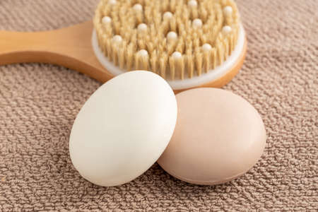 Close up of soap bar lies on towel background next to bamboo brush for massaging. Eco friendly space and personal hygiene conceptの写真素材