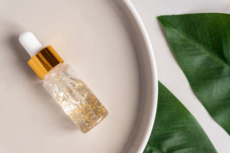 transparent bottle with beauty serum, hyaluronic acid, 24k gold and vitamins on a trayl. Home face and body care conceptの写真素材