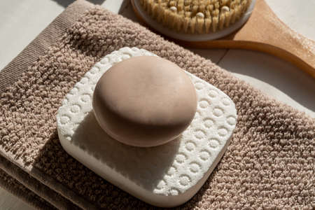 Close up of soap bar lies on towel background next to bamboo brush for massaging. Eco friendly space and personal hygiene conceptの写真素材
