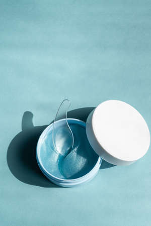 Modern cosmetic concept. Sparkling blue facial eye patches in plastic jar. Hydrogel patch. Anti aging and lifting cosmetics. Face skin care. Hydrating and wrinkles patch. Mockup.の写真素材