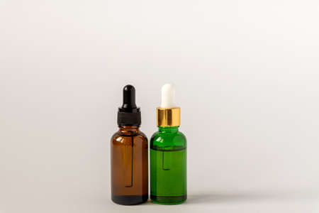 Amber and green glass serum bottles with dropper on white background. Assortment of unbranded products for face and body care. Copy space.の写真素材