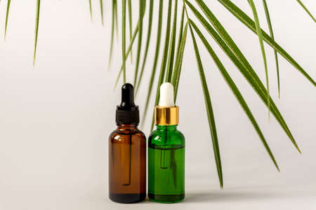 Amber and green glass serum bottles with dropper on white background. Assortment of unbranded...