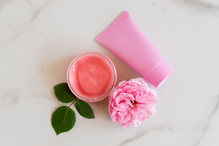 Hygiene bath product. Body, face rose scrub with blooming pink rose flowers on marble background. Wellness therapy regeneration and skin care conceptの写真素材