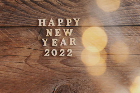 Happy New Year 2022. Symbol made from wooden letters and numbers 2022 on wooden background with...