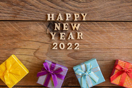 Happy New Year 2022. Quote made from wooden letters and numbers 2022 on wooden background with...