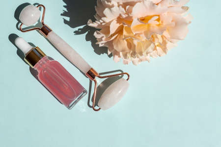 transparent bottle with beauty serum, hyaluronic acid and rose water on a blue background with...