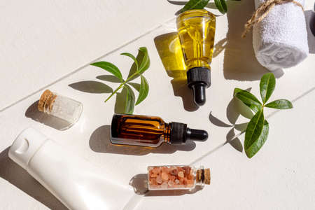 Natural essential oils in glass dropper bottles with himalayan salt, cotton towel on wooden...
