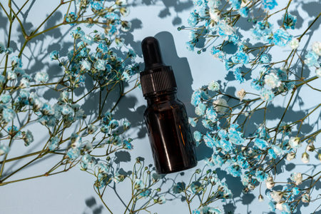 Top view of Beauty oil with natural ingredients on a blue background with gypsophila flowers. Skin care treatment concept. Unbranded package for design.の写真素材
