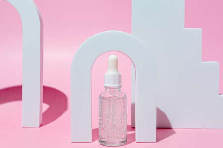 Cosmetic bottle from glass with dropper in the geometrical arch. Pastel colors, cosmetics mockup...