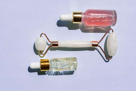 Massage quartz roller for face of pink natural nephritis with beauty 24k gold serum oil and rose elixir. Skin care facial massage and relaxation. Gua Sha massage tools. Anti age and lifting at homeの写真素材