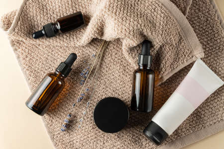 Set of natural organic SPA beauty products on brown towel. Homemade face oil, moisturizer cream jar, amber glass spray bottle on beige backgroundの写真素材
