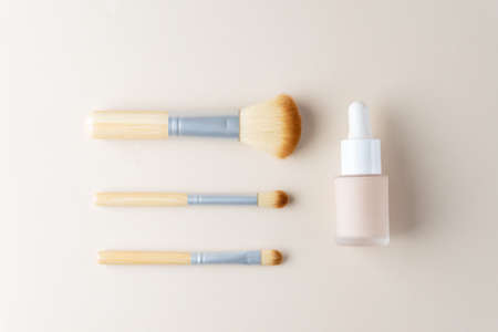 LiquidFoundation in a pipette glass bottle on a beige background. Face corrector with makeup brushes with copy space. Packaging mockup.の写真素材