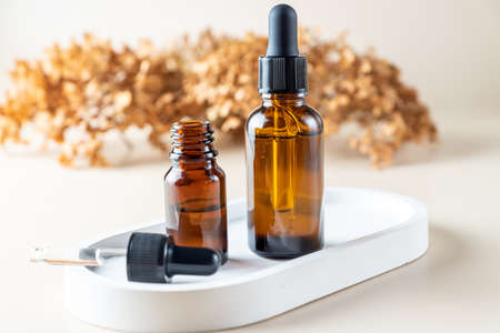 Face serum dropp bottles on a tray on beige background. Home routine skin care cosmetic set. Unbranded bottles for your designの写真素材