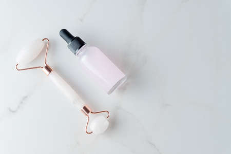 Organic skin care concept. Rose quartz roller and glass dropper bottle with essential oil. Eco friendly skincare and treatment at home.の写真素材