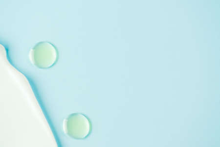 Face or body cream and drops of beauty oil on blue background with copy space. Cosmetic products textureの写真素材