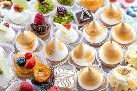 Assorted different mini cakes with cream, chocolate and berries- Sweets offered at the pastry shop.
