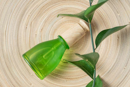 Dropper bottle with beauty face serum on bamboo plate with green leaves. Eco style unbranded green package. Skin care concept.の写真素材