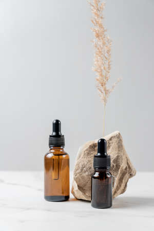 Serum glass bottles with pipette near natural stone on gray background. Natural Organic Spa Cosmetic concept. Front view. Place for your textの写真素材