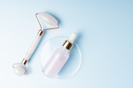 Massage quartz roller for the face of pink natural nephritis with beauty serum or essential oil. Skin care facial massage and relaxation. Home massage tools. Anti age and lifting proceduresの写真素材