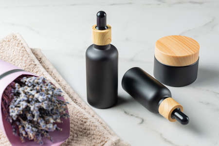 Lavender essential oil skin care natural cosmetics in black elegant bottles on marble table. Set of bottles and jar cosmetology cosmeticsの写真素材