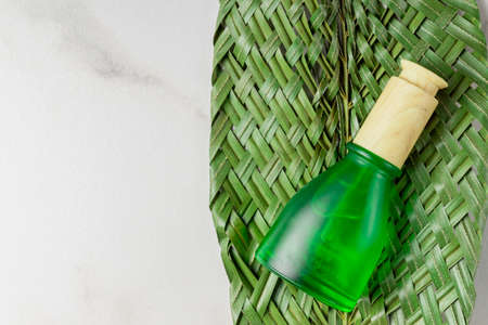 Blank green frosty glass essential oil bottle with pipette on marble background decorated green tropical leaf. Skin care concept with natural cosmeticsの写真素材