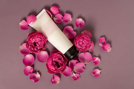 Beauty treatment. Tube with pink roses on a dark pink background. Beauty Spa and Wellness, anti-aging treatments with rose petals. The concept of youth.の写真素材