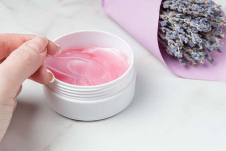 Female hands are taking eye patches out from the container with the spoon. Anti aging concept. eye pstches with lavender extract. Anti wrinkle protection. skincare lifestyle.の写真素材