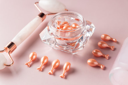 Pink quarts face roller and single dose serum capsules in a package. facial massage. natural cosmetic treatment. monochromatic look, knolling conceptの写真素材