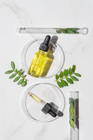 cosmetic skincare background. Herbal medicine with green leaves. Beauty spa product, top view. Laboratory glass petri with pipette dropper of serum, oil, beauty productの写真素材