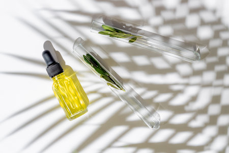 Organic cosmetic product, natural ingredient and laboratory glassware on white background, top view. Retynol serum in dropper bottle and test tube with herb samples.の写真素材